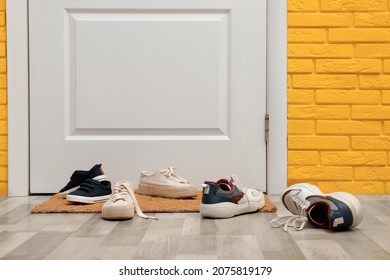 Stylish shoes and mat near door in hallway