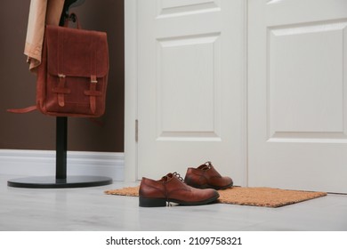 Stylish Shoes On Door Mat Near Coat Rack In Hall