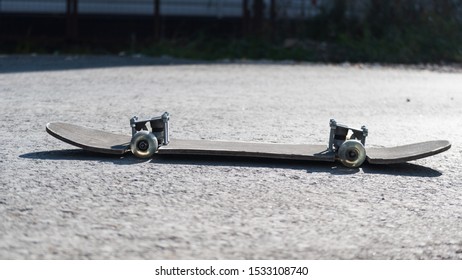 Stylish Skateboard On Asphalt Road. Redone And Understated. A Battered Old Wench With A Skinned Head. Old School Style. Sunny Autumn Day With Skateboard. Skateboard Style. Lifestyle On The Board.