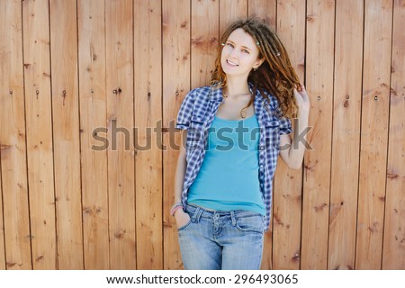 Stylish slim girl with dreadlocks on wooden wall background.