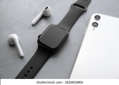 Stylish Smart Watch, Phone And Earphones On Grey Stone Table, Closeup