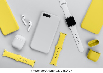 Stylish smart watch, phone, earphones and cases on gray background