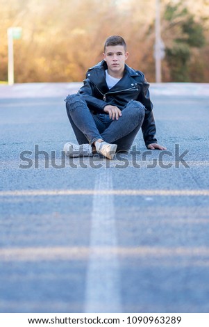 Stylisch lächelnder Teenager, der auf der Straße sitzt.