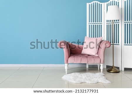 Stylish sofa, lamp and folding screen near blue wall