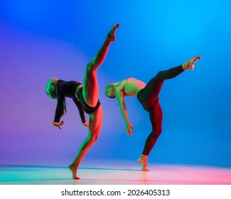 Stylish Sportive Caucasian Couple Of Dancers Dancing Contemporary Dance On Colorful Gradient Blue Pink Background In Neon Light. Concept Of Art, Creativity, Movement, Style And Fashion, Action.