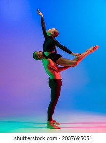 Stylish Sportive Caucasian Couple Of Dancers Dancing Contemporary Dance On Colorful Gradient Blue Pink Background In Neon Light. Concept Of Art, Creativity, Movement, Style And Fashion, Action.