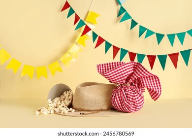 Stylish straw hat, popcorn, bundle bag and flags for Festa Junina celebration on color background