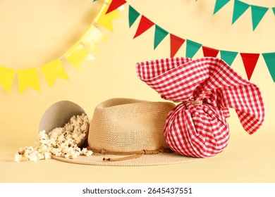 Stylish straw hat, popcorn, bundle bag and flags for Festa Junina celebration on color background