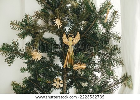 Stylish straw ornaments on fir branches in festive room. Simple eco decoration, straw stars and angel on christmas tree branches. Ukrainian traditional ornaments. Holiday decor Stock photo © 