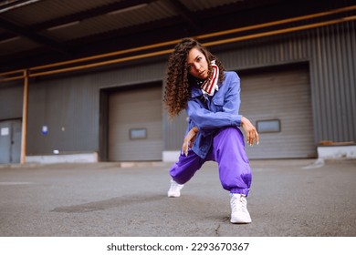 Stylish street dancer with American bandana is dancing. A young dancer in stylish clothes shows the movements. The concept of dance and sports.
