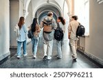 Stylish students are walking along the hall of the university and talking. The students with backs to the camera and are carrying backpacks on their shoulders.The concept of admission, back to school.