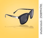 Stylish sunglasses in air on yellow background