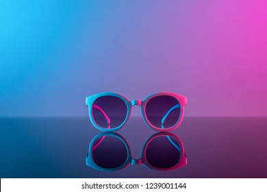 Stylish sunglasses shot using pink and blue abstract colored lighting with copy space.