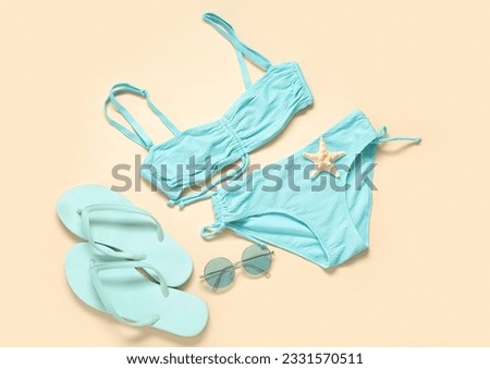 Stylish swimsuit, flip-flops and sunglasses on color background