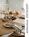 Stylish table setting with beautiful dishware, glasses and autumn decor in dining room