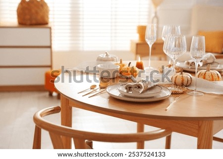 Stylish table setting with beautiful dishware and autumn decor in dining room