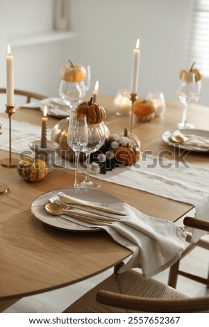 Stylish table setting with beautiful dishware, glasses and autumn decor in dining room