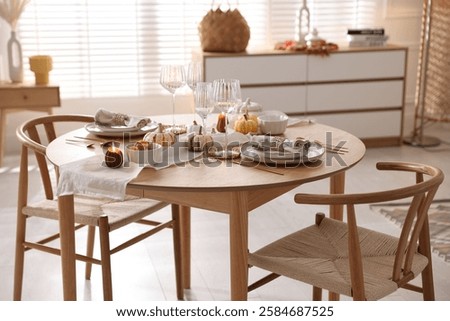 Stylish table setting with beautiful dishware and autumn decor in dining room