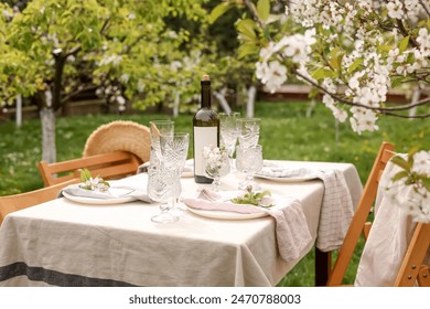 Stylish table setting with beautiful spring flowers, wine, plates and glasses in garden - Powered by Shutterstock