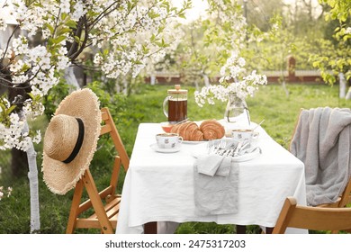 Stylish table setting with beautiful spring flowers, tea and croissants in garden - Powered by Shutterstock