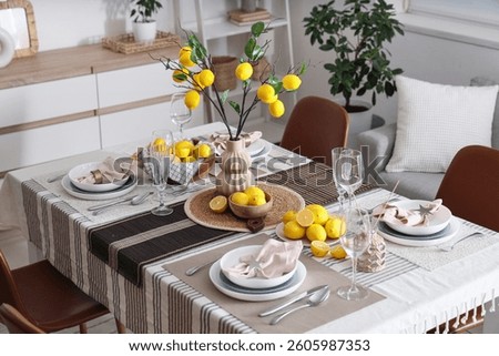 Stylish table setting decorated with many fresh citruses and beautiful lemon tree branches in dining room
