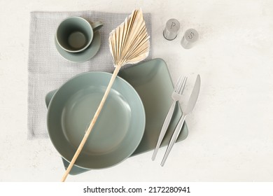 Stylish table setting and decorative palm leaf on light background - Powered by Shutterstock