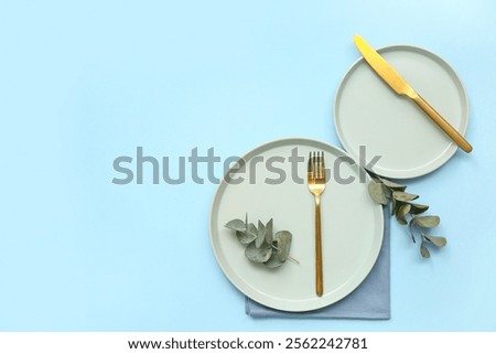Stylish table setting with eucalyptus on blue background