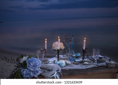 Stylish table setting in nautical style by the sea at sunset. Romantic candlelit dinner by the ocean.
 - Powered by Shutterstock