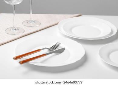 Stylish table setting with white dishware on white tablecloth