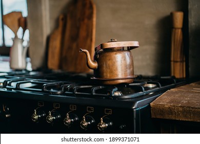 Stylish Teapot Made Of Metal Steel Copper Stands On A Vintage Gas Stove. Autumn Old Stylish Kitchen In The Apartment, Sunny Daylight From The Window. Copy Space.