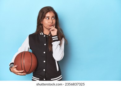 Stylish teen with basketball, embracing sports fashion looking sideways with doubtful and skeptical expression. - Powered by Shutterstock