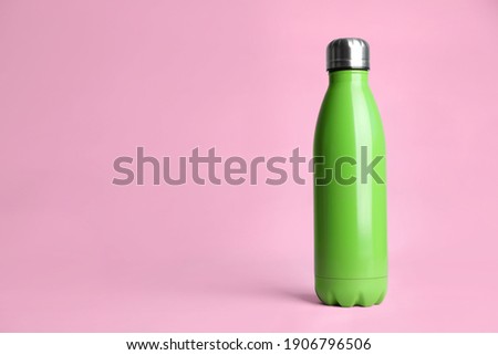 Stylish thermo bottle on pink background, space for text