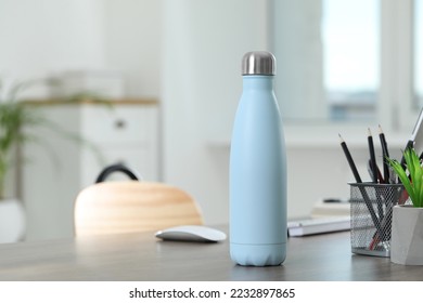 Stylish thermo bottle on wooden table at home. Space for text - Shutterstock ID 2232897865