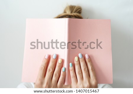 Stylish trendy color female manicure . Woman’s hands keep pink note pad