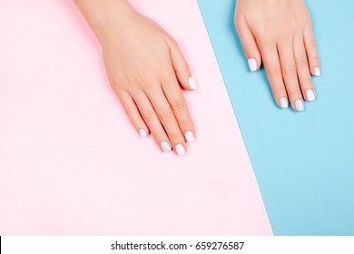 Stylish trendy female manicure. Beautiful young woman's hands on pink and blue background.