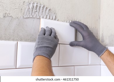 Stylish Trendy White Ceramic Tile With A Chamfer On The Kitchen Wall. Tiler Hands In The Process Of Laying White Rectangular Tiles On Bathroom Wall.  Repair Of Apartments And Bathrooms. 