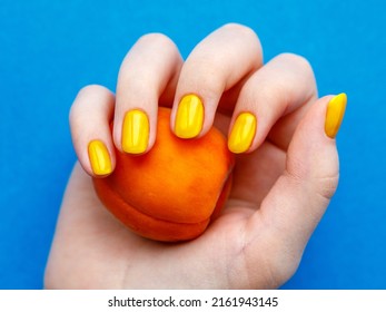 Stylish trendy yellow nails and nail polish with apricot on bright blue background. Young teen girl fingers. Manicure nail painting, beauty salon concept. Summer beauty hand top view close up - Powered by Shutterstock