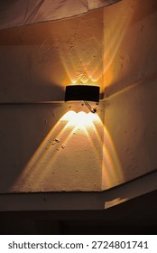 Stylish wall light casting warm rays on a textured wall, creating interesting shadow patterns ideal for architectural or interior design projects with copy space