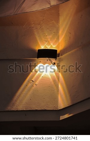 Stylish wall light casting warm rays on a textured wall, creating interesting shadow patterns ideal for architectural or interior design projects with copy space