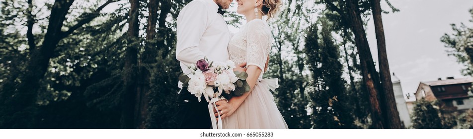 Stylish Wedding Bride And Groom Hugging In Sunny Park, Sensual Moment. Modern Couple  Embracing In Garden In Light. Fine Art Wedding Photo, Romantic Tender Moment, Long Edge