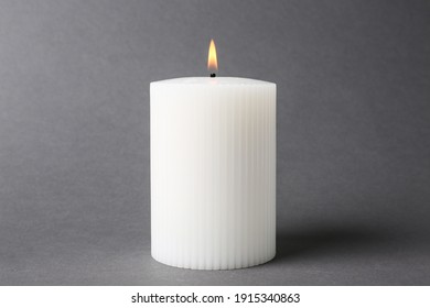 Stylish white burning candle on grey background