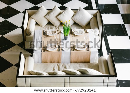 Stylish white dining table and sofas. Minimalist interior in monochrome. Black and white concept. Empty restaurant top view. Close-up