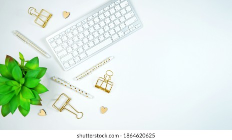 Stylish white and gold theme desktop workspace with keyboard, notebooks and smart phone. Top view blog hero header creative composition flat lay. - Shutterstock ID 1864620625