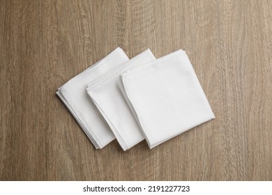 Stylish white handkerchiefs on wooden table, flat lay