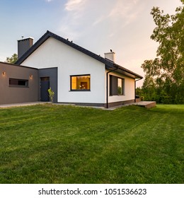 Stilvolles, weißes Haus mit großem grünem Rasen, im Freien