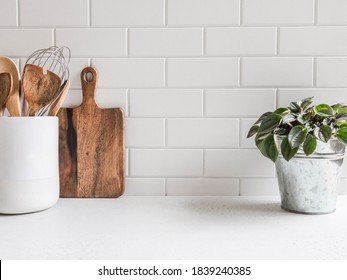 Stylish white kitchen background with kitchen utensils and green houseplant standing on white countertop, copy space for text, front view - Shutterstock ID 1839240385