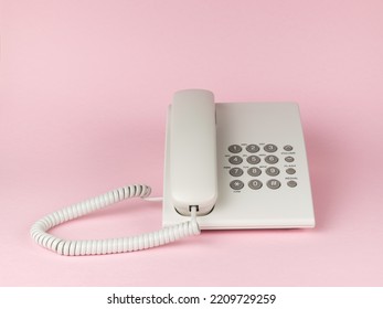 Stylish White Wired Office Phone On Pink Background. The Concept Of Telephone Communication. Flat Lay.