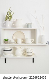 stylish white wooden shelves on a white textured wall with a set of dishes of their eco materials. beautiful design in a modern kitchen. - Shutterstock ID 2256932433