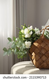 Stylish Wicker Basket With Bouquet Of Flowers On Ottoman In Room