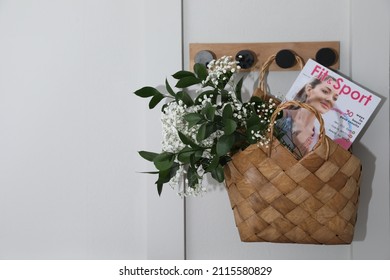 Stylish Wicker Basket With Bouquet Of Flowers And Magazine Hanging On Wooden Rack Indoors, Space For Text